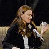 a woman holds a glass ball in front of a microphone that says hollywood on it