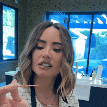 a woman in a plaid shirt is holding a toothpick in her mouth