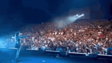 a woman stands on a stage in front of a large crowd