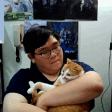 a man wearing glasses is holding an orange and white cat .