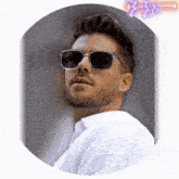a man wearing sunglasses and a white shirt looks to the side