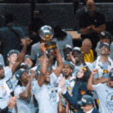 a group of men are holding a trophy in their hands