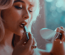 a close up of a woman applying lipstick with the watermark dailunari on the bottom right