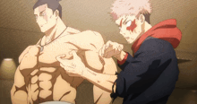 a man in a red hoodie is touching another man 's muscles