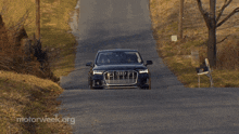 a black audi is driving down a road with motorweek.org written on the bottom