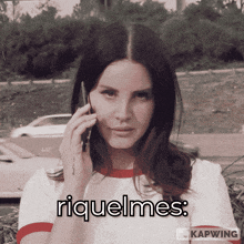 a woman talking on a cell phone with the words riquelmes on the bottom