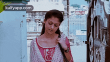 a woman in a pink and white dress is standing in front of a building .