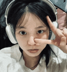 a girl wearing headphones is giving the peace sign