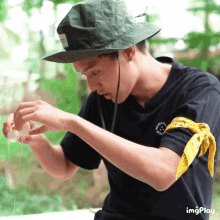 a man wearing a hat and a black shirt has a bandana around his arm that says ' imgplay '