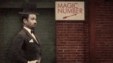 a man in a tuxedo is holding a rabbit and a sign with the number four on it