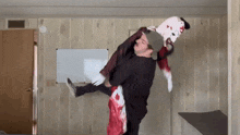 a man is carrying a clown in his arms in front of a white board