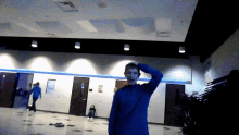 a boy in a blue sweater stands in a hallway