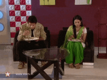 a man and a woman are sitting at a table with plates of food and a star on the bottom right