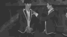 a couple of men in suits are standing next to each other in a black and white photo .