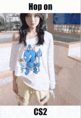 a girl wearing a white shirt with a blue monster on it and the words hop on cs2 below her