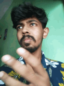 a man with a beard is wearing a blue shirt with yellow flowers