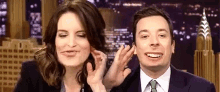 a woman is touching a man 's ear while they are making funny faces .