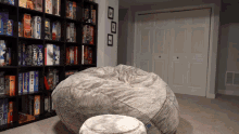a large bean bag chair sits in front of a bookshelf filled with board games including legacy
