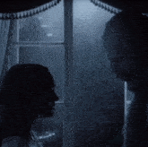 a man and a woman are standing in front of a window