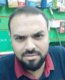 a man with a beard is making a funny face in front of a green wall that says oppo on it