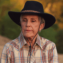 a woman wearing a plaid shirt and a black hat