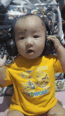 a baby wearing headphones and a yellow shirt that says " birdword "