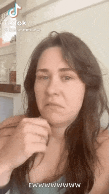 a woman with long hair is making a funny face with her hands on her chin .