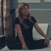 a woman is sitting on a bed and the word okay is visible behind her