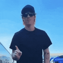 a man wearing sunglasses and a black shirt is giving a thumbs up