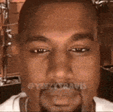 a close up of kanye west 's face with a beard and a white shirt .