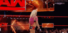 a female wrestler is standing in a wrestling ring with a crowd watching .