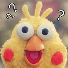 a stuffed yellow chicken with big eyes and a red beak is making a surprised face .