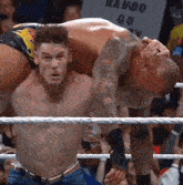 two men are wrestling in a ring with a sign that says rambo go