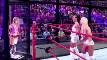 two female wrestlers are standing in a wrestling ring with a crowd watching .