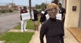 a group of people are standing on a sidewalk holding signs for a candidate .