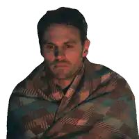 a man is wrapped in a plaid blanket and looking at the camera