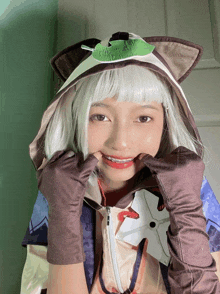 a girl wearing a cat costume with a green leaf on the hood