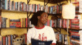 a woman in a white shirt is standing in front of a bookshelf filled with books .