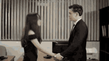 a man and a woman are shaking hands in a room .