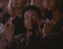 a man in a suit and tie is giving the middle finger in a crowd of people .