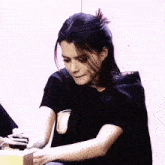 a woman in a black shirt is sitting at a desk