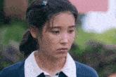 a woman with a flower in her hair looks down