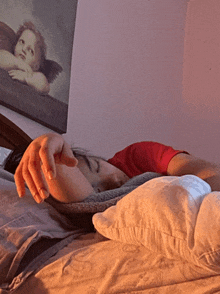 a person laying on a bed with a painting of an angel on the wall