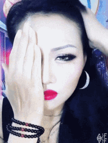 a woman covering her face with her hand and has a bracelet on her wrist with the letter a on it