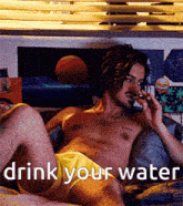 a shirtless man laying on a bed with the words drink your water written above him