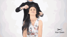 a woman in a floral dress is getting her hair cut by a woman in a black sweater .