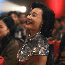 a woman in a sequined top is smiling in a crowded room
