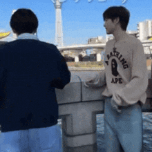 a man in a bathing ape sweater stands next to another man