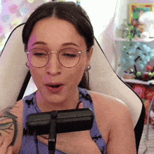 a woman with glasses and a tattoo on her arm is holding a microphone