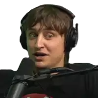 a man wearing headphones stands in front of a microphone with his mouth open